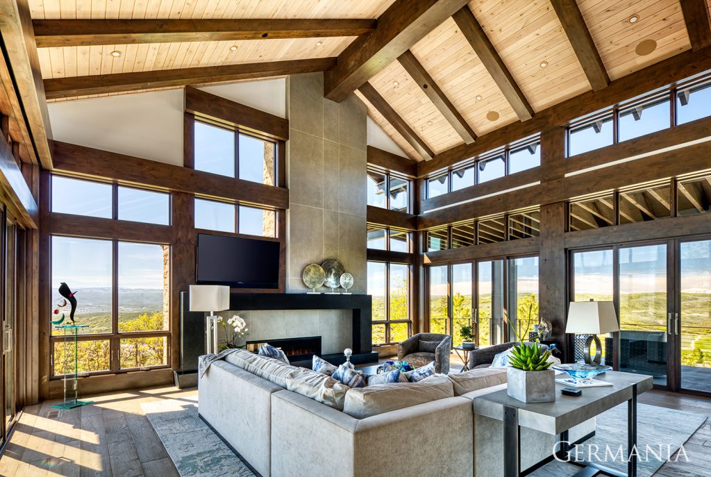 Just an incredible image with tongue and groove ceilings, wood beams arching high above, wood floors, and windows which offer an optimal view of the landscape.