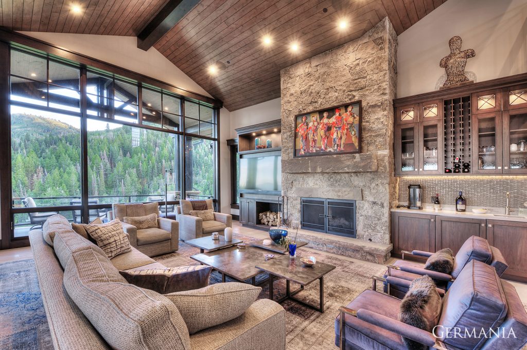 In this high end custom home living room by Germania, tongue and groove ceilings, stone fireplace with rustic mantle, and cabinetry design were meticulously crafted and designed.