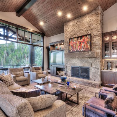 In this high end custom home living room by Germania, tongue and groove ceilings, stone fireplace with rustic mantle, and cabinetry design were meticulously crafted and designed.