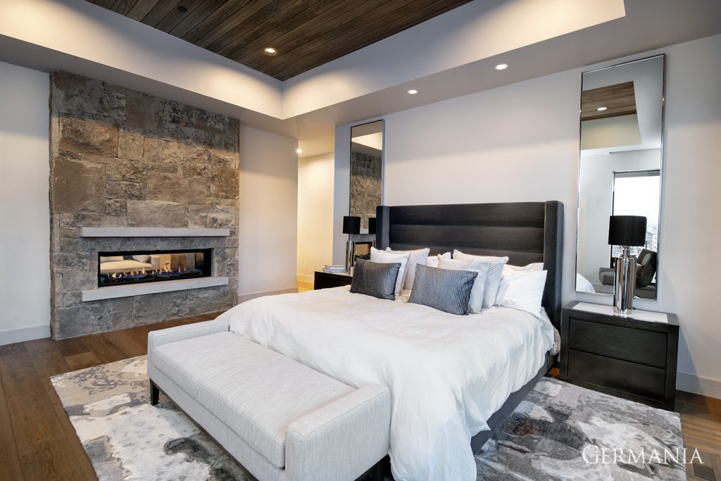 Cozy bedroom with gas fireplace and rock fireplace surround with a modern look with rustic touches.