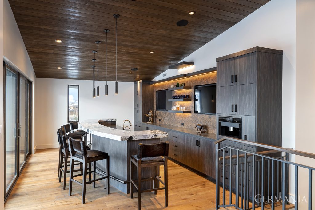 Custom dark wood kitchen with dark paneled ceiling, curved bar, and a view of the outside.