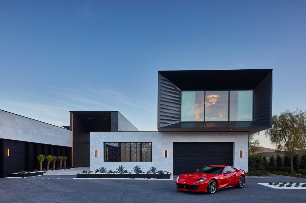 A red sports car stands in contrast to the black and white exterior of this modern industrial home.