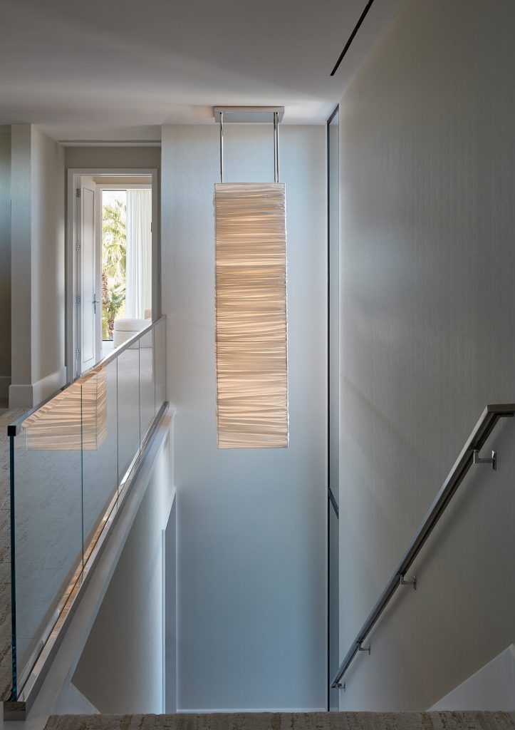 A large chandelier illuminates the space above and below this stairway.