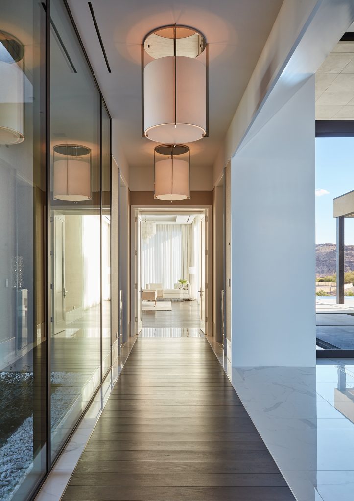 Cylindrical lights illuminate this beautiful glass lined hallway.