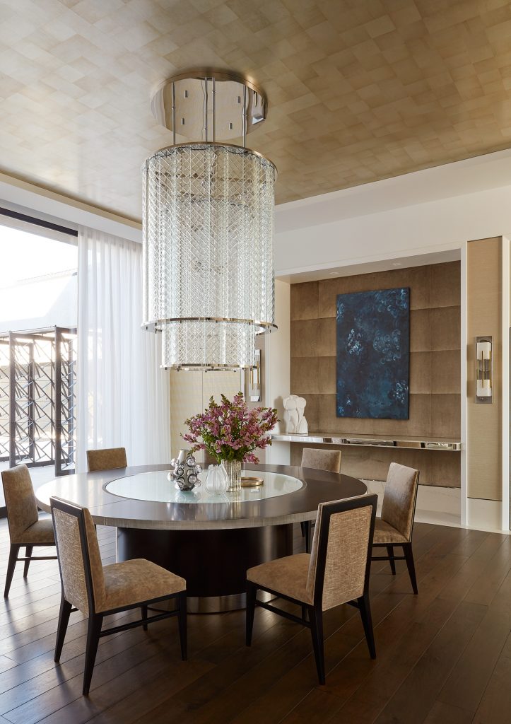 Custom artwork, an elegant chandelier, and a round table complete this dining room aesthetic.