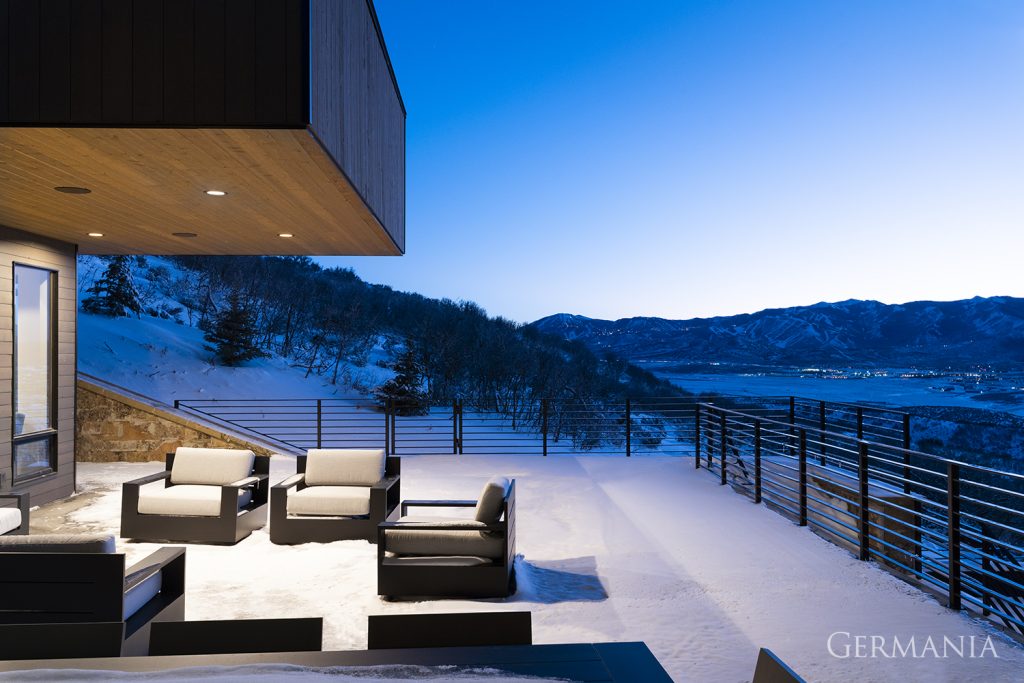 The snow covers the seating area in this spacious deck of this mountain home.