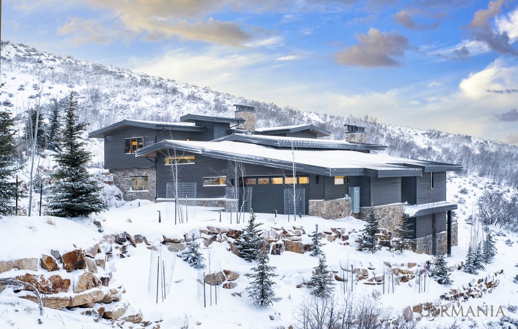 Snow covers the front yard of this modern mountain home.