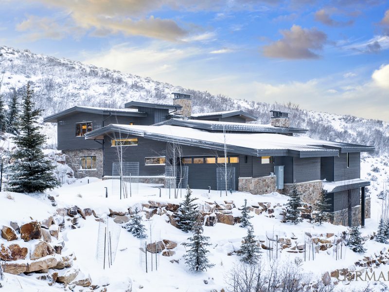 Snow covers the front yard of this modern mountain home.