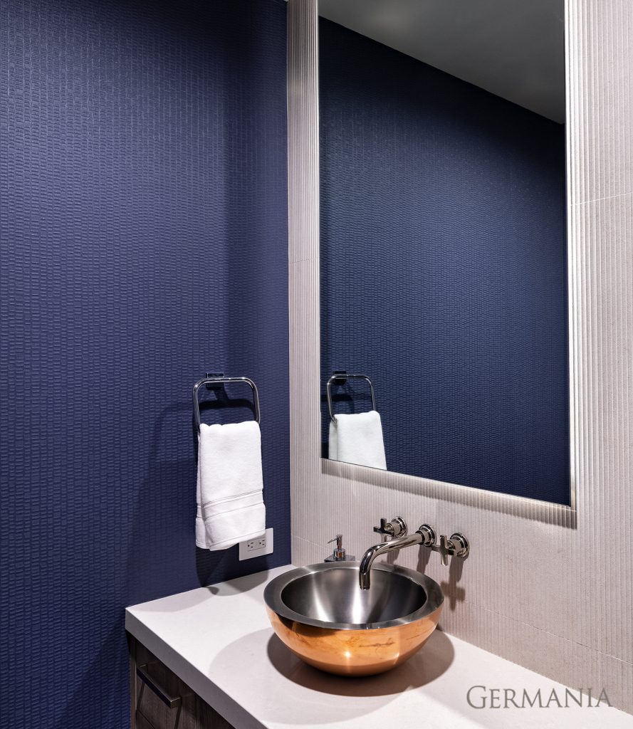 Deep blue textured wallpaper makes this powder bath feel luxe.