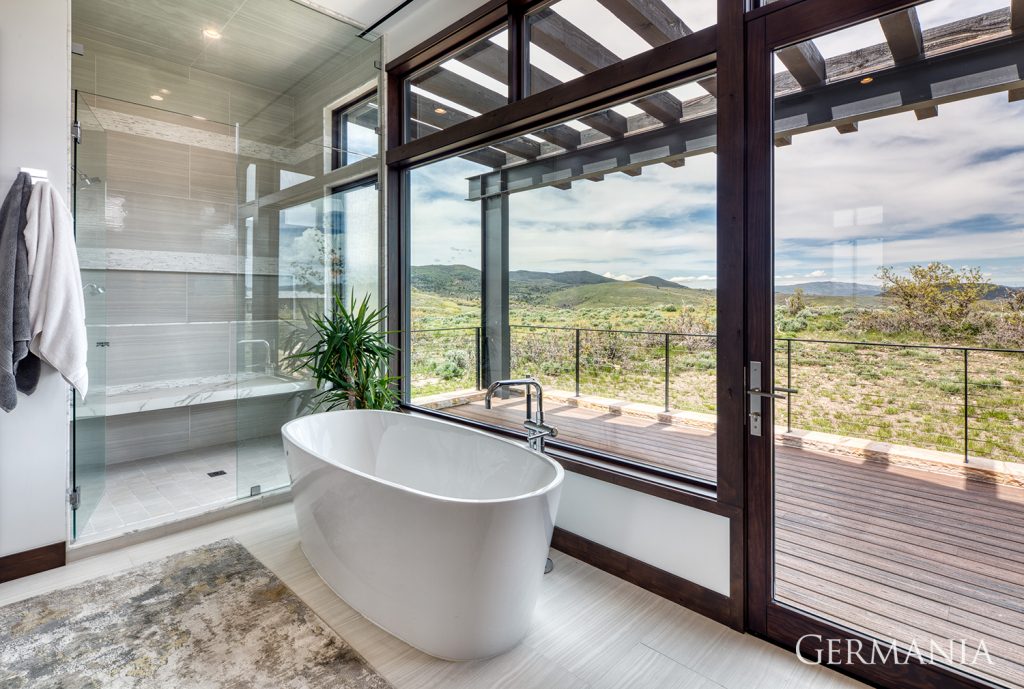 Luxury, custom-built bathroom with high-end bathtub and shower looking out over stunning mountain views.