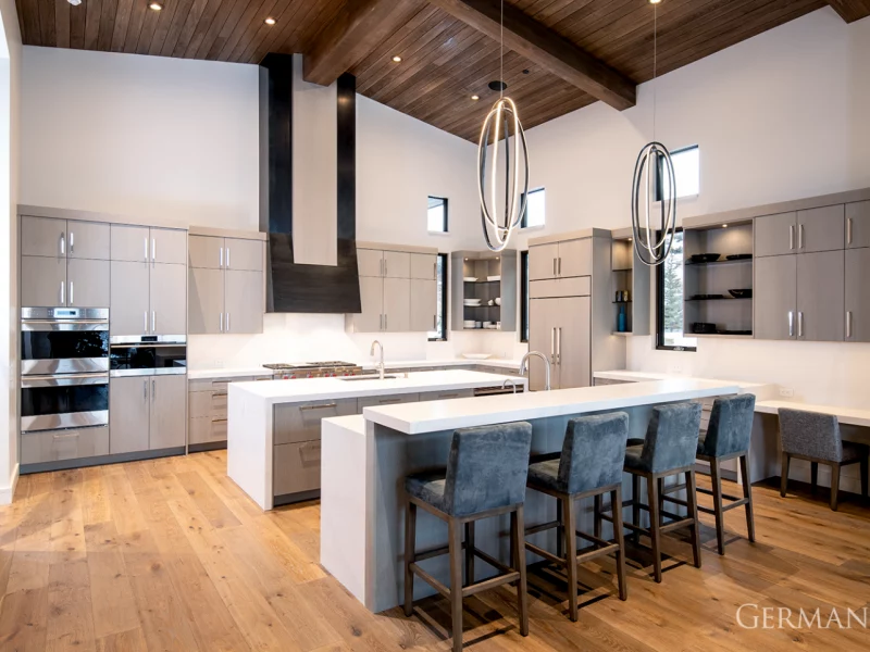 High-end, custom-built, luxury kitchen in Park City, UT with stunning light fixtures, white marble counters, and dark wood ceiling.
