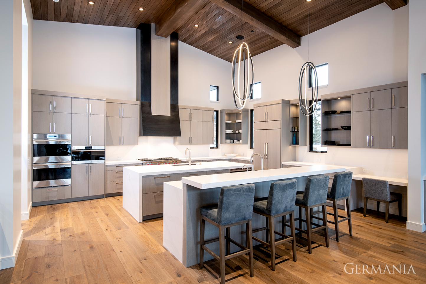 High-end, custom-built, luxury kitchen in Park City, UT with stunning light fixtures, white marble counters, and dark wood ceiling.